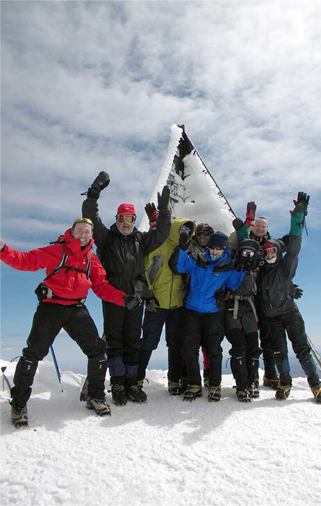 Happy expedition members waving at summit